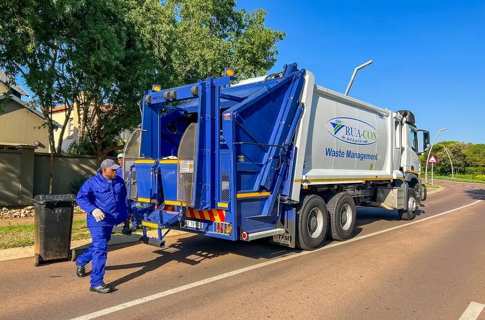 Rua-Con crew member wheeling a refuse bin to the rear of a compactor truck