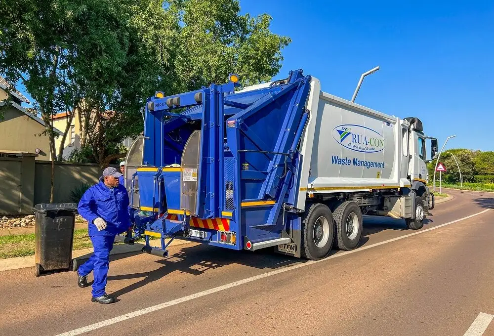 Rua-Con crew member wheeling a refuse bin to the rear of a compactor truck