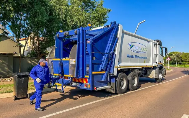 Rua-Con crew member wheeling a refuse bin to the rear of a compactor truck