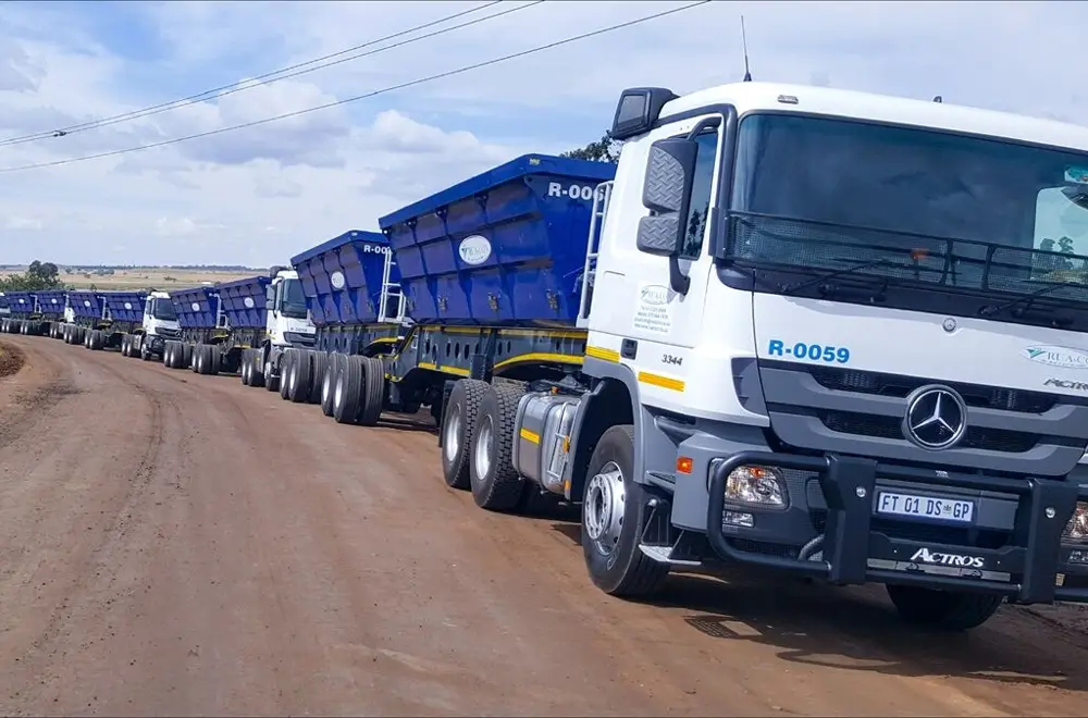 Rua-Con truck tractor with side-tipper trailers on a dirt road