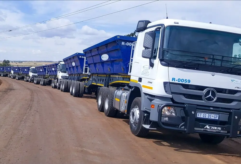 Rua-Con truck tractor with side-tipper trailers on a dirt road