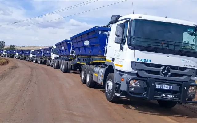 Rua-Con truck tractor with side-tipper trailers on a dirt road
