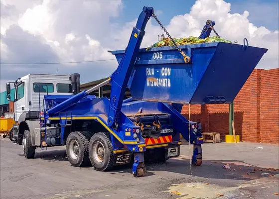 Rua-Con skip loader truck lifting a blue skip